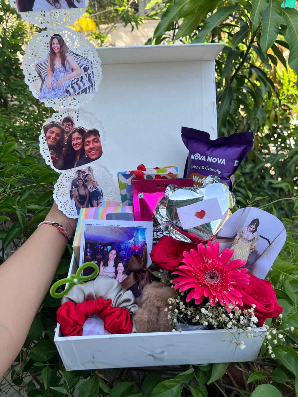 An open celebration box with photographs, flowers, snacks and keepsakes