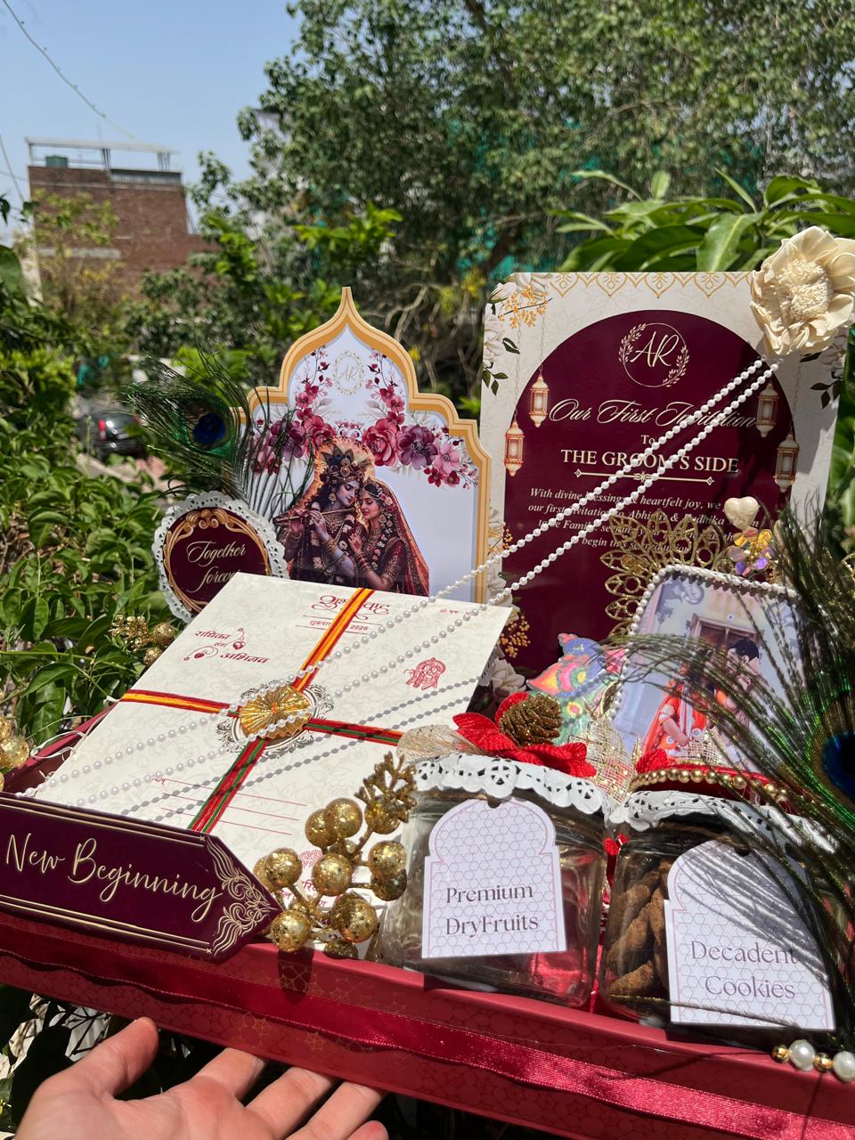 A red and gold first wedding invitation hamper with dry fruits and keepsakes